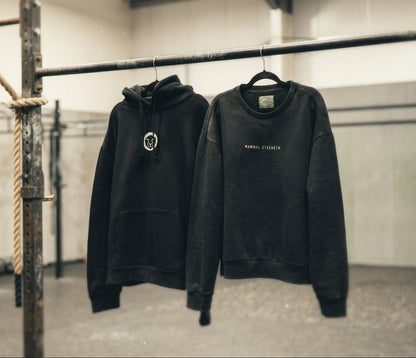 Two Mammal Strength black training sweatshirts hanging in a gym – premium weightlifting apparel
